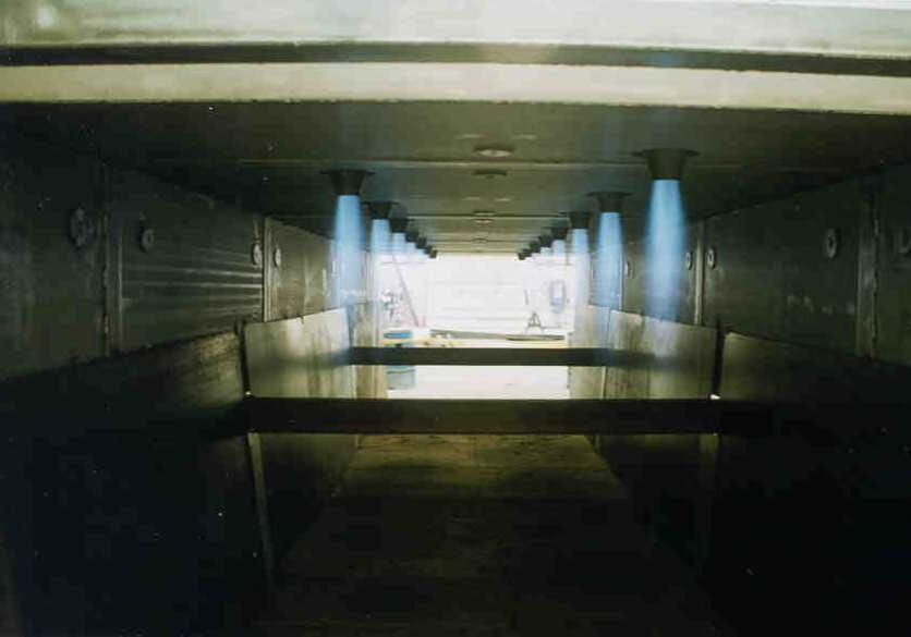 A long hallway with benches and lights on the wall.